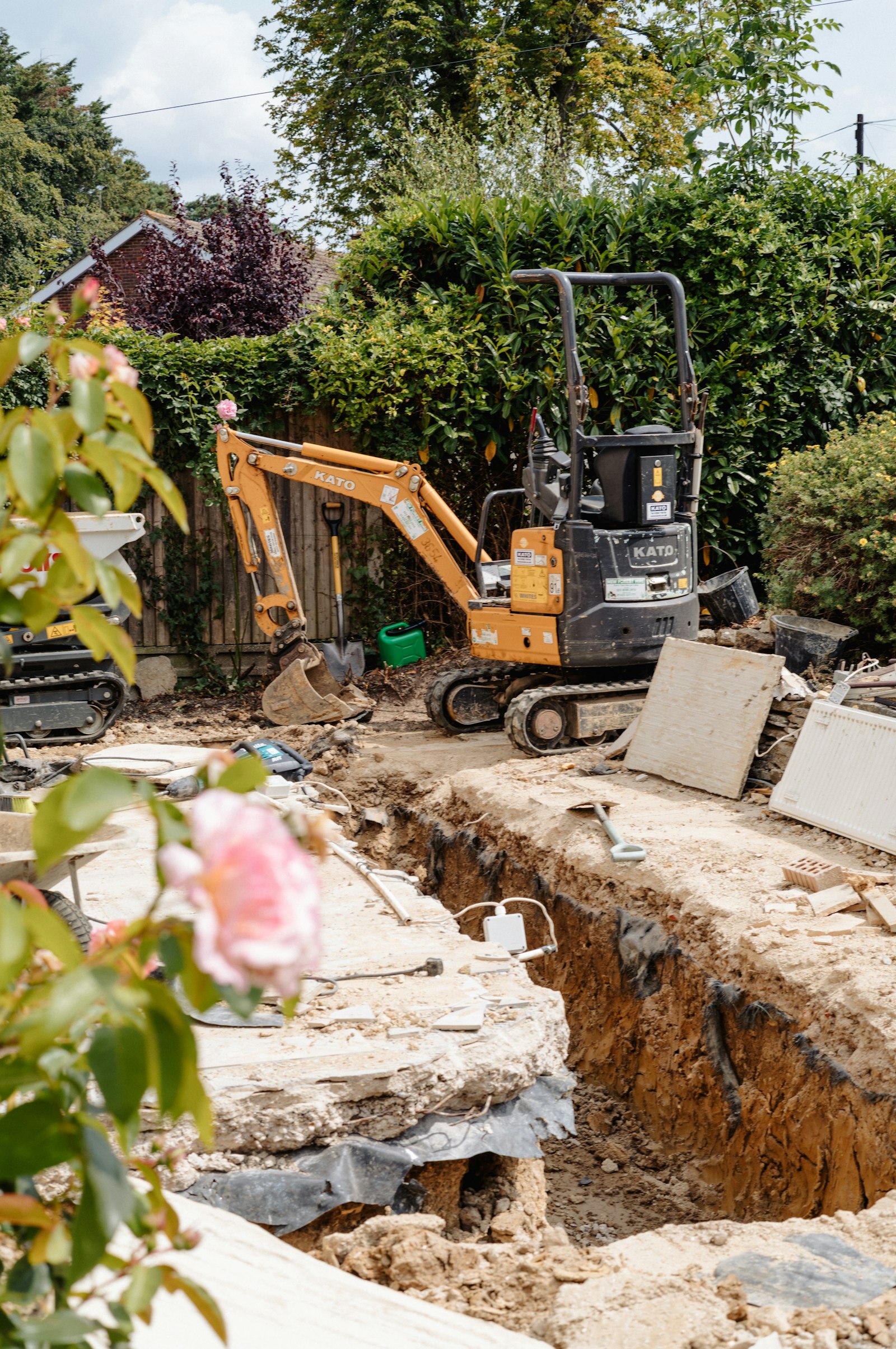 Mini digger beside a trench in a garden